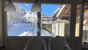 Ein Essbereich mit Tisch und Stühlen, ein Fenster mit Blick auf eine verschneite Landschaft und einer Lampe.
