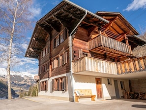 Eine Holzchalet mit Balkon, einer Holzbank und Blick auf die Berge.