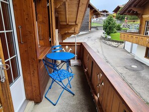 Ein Holzbalkon mit Tisch und Stühlen, mit Blick auf eine Wohnstraße.