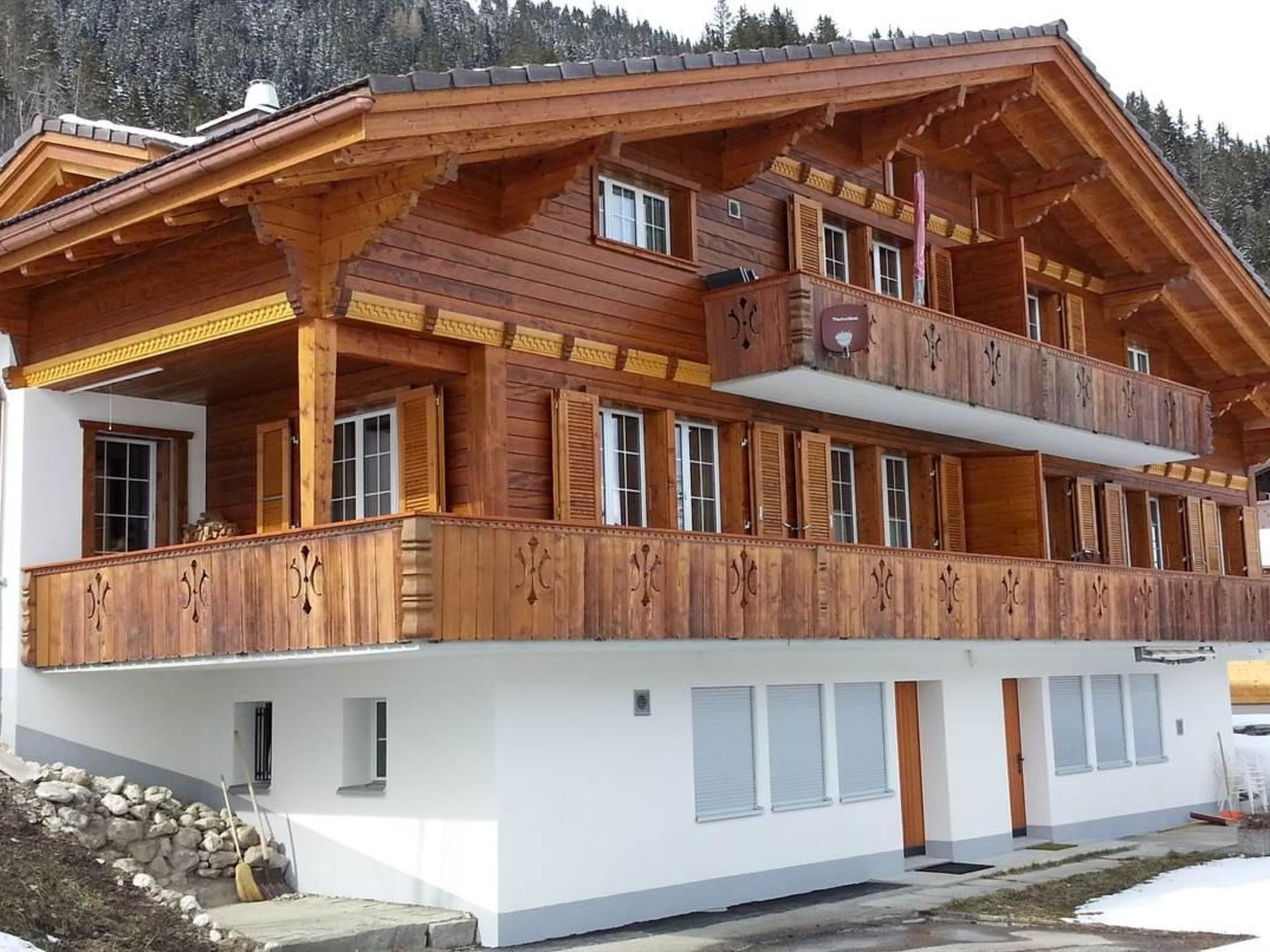 A two-story wooden building with balconies, large windows, and a white base.