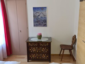 Una habitación con un aparador de madera, una silla, un cuadro colgado en la pared y una puerta.