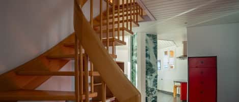 A wooden staircase leading to a room with a tiled floor and a red cabinet.