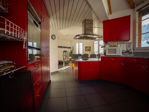 Eine moderne Küche mit roten Schränken, einer Mikrowelle und einem Essbereich mit Stühlen und einem Tisch.