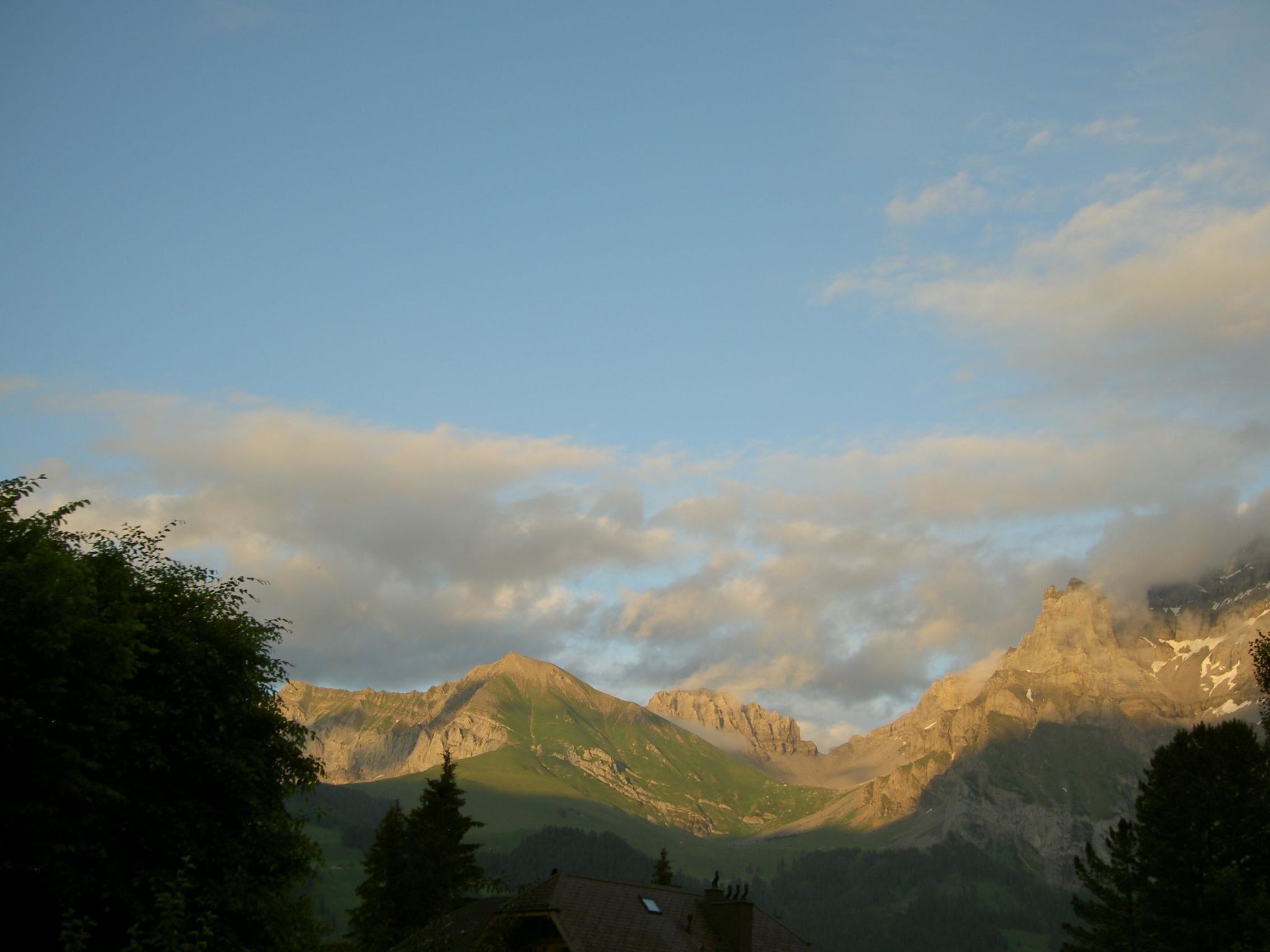 Paesaggio montuoso con cielo sereno e un piccolo edificio con tetto spiovente.