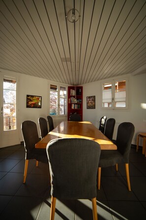 Une salle de conférence avec une longue table, des chaises, une bibliothèque et des tableaux encadrés accrochés aux murs.
