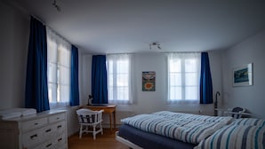 Ett sovrum med en säng, ett skrivbord, en stol, en byrå och en affisch på väggen.