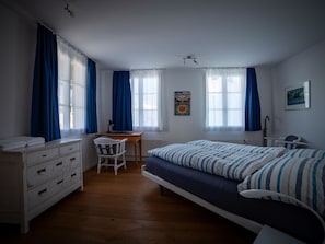 A bedroom with a bed, a desk, a chair, a dresser, and a poster on the wall. - Surselva Appartement/Fewo, Dusche, WC, Balkon 6-Zimmerwohnung by Interhome (Adelboden)