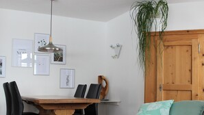 En matplats med ett träbord, svarta stolar och en hängande taklampa.