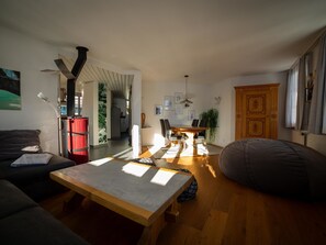 A modern living room with a wooden coffee table, a sofa, a red cabinet, and a dining area with a table and chairs. - Surselva Appartement/Fewo, Dusche, WC, Balkon 6-Zimmerwohnung by Interhome (Adelboden)