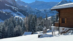 A wooden chalet with a snow-covered roof, surrounded by snow-laden trees and mountains in the background. - Im Rägeboge Appartement/Fewo, Bad, WC, 2 Schlafräume 3-Zimmerwohnung Dachstock by Interhome (Adelboden)