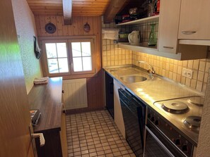 Eine kleine Küche mit Fenster, Spüle und Herd.