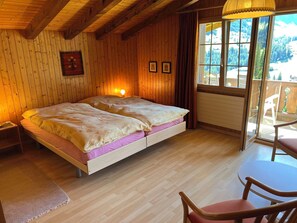 Ein Zimmer mit Holzwandverkleidung, einem Bett, einem Tisch und einem Stuhl.