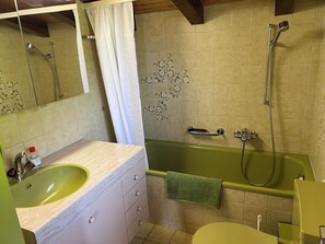 Ein Badezimmer mit einer grünen Badewanne, einem Waschbecken mit Spiegel und einer Toilette.
