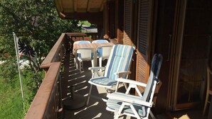 A covered outdoor seating area with patio chairs and a table, overlooking a garden. - Im Rägeboge Appartement/Fewo, Bad, WC, 2 Schlafräume 3-Zimmerwohnung Dachstock by Interhome (Adelboden)