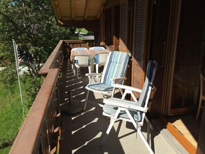 Ein überdachter Außenbereich mit Terrassenstühlen und einem Tisch mit Blick auf einen Garten.