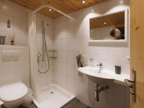 Ein Badezimmer mit Dusche, Toilette, Waschbecken und Spiegel.