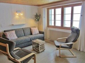 A living room with a sofa, two chairs, a wooden crate, and a radiator. - Gästehaus Alpengruss Appartement/Fewo, Dusche, WC, 1 Schlafraum by Interhome (Adelboden)
