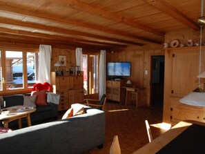 Ein gemütliches Blockhauss-Interieur mit einer Couch, einem Fernseher und Holzwänden.
