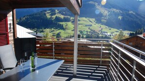 Eine Terrasse mit Tisch und Stühlen mit Blick auf eine Berglandschaft.