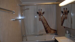 Ein Badezimmer mit Dusche, Waschbecken und einem Spiegel, der eine Giraffe widerspiegelt.