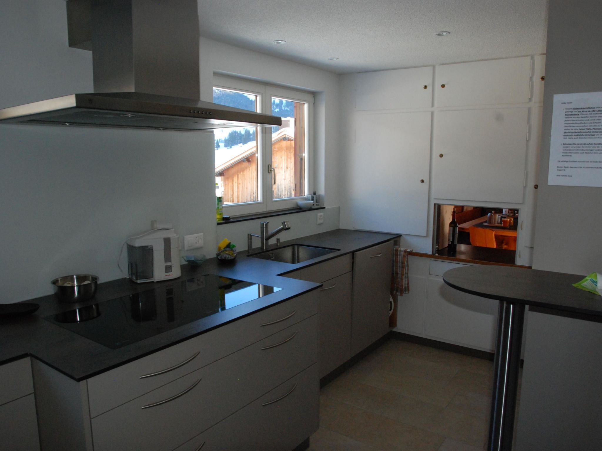 Una cocina moderna con ventana, electrodomésticos de acero inoxidable y vistas a una terraza de madera.
