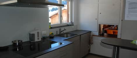 Una cocina moderna con ventana, electrodomésticos de acero inoxidable y vistas a una terraza de madera.