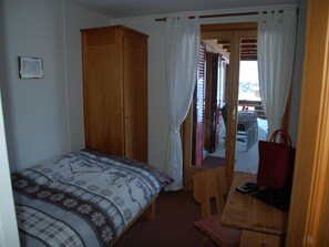A bedroom with a bed, a wooden wardrobe, a desk with a chair, and a view through a door. - Hubelhüsi Appartement/Fewo, Dusche oder Bad, WC, 4 oder mehr Schlafräume by Interhome (Adelboden)
