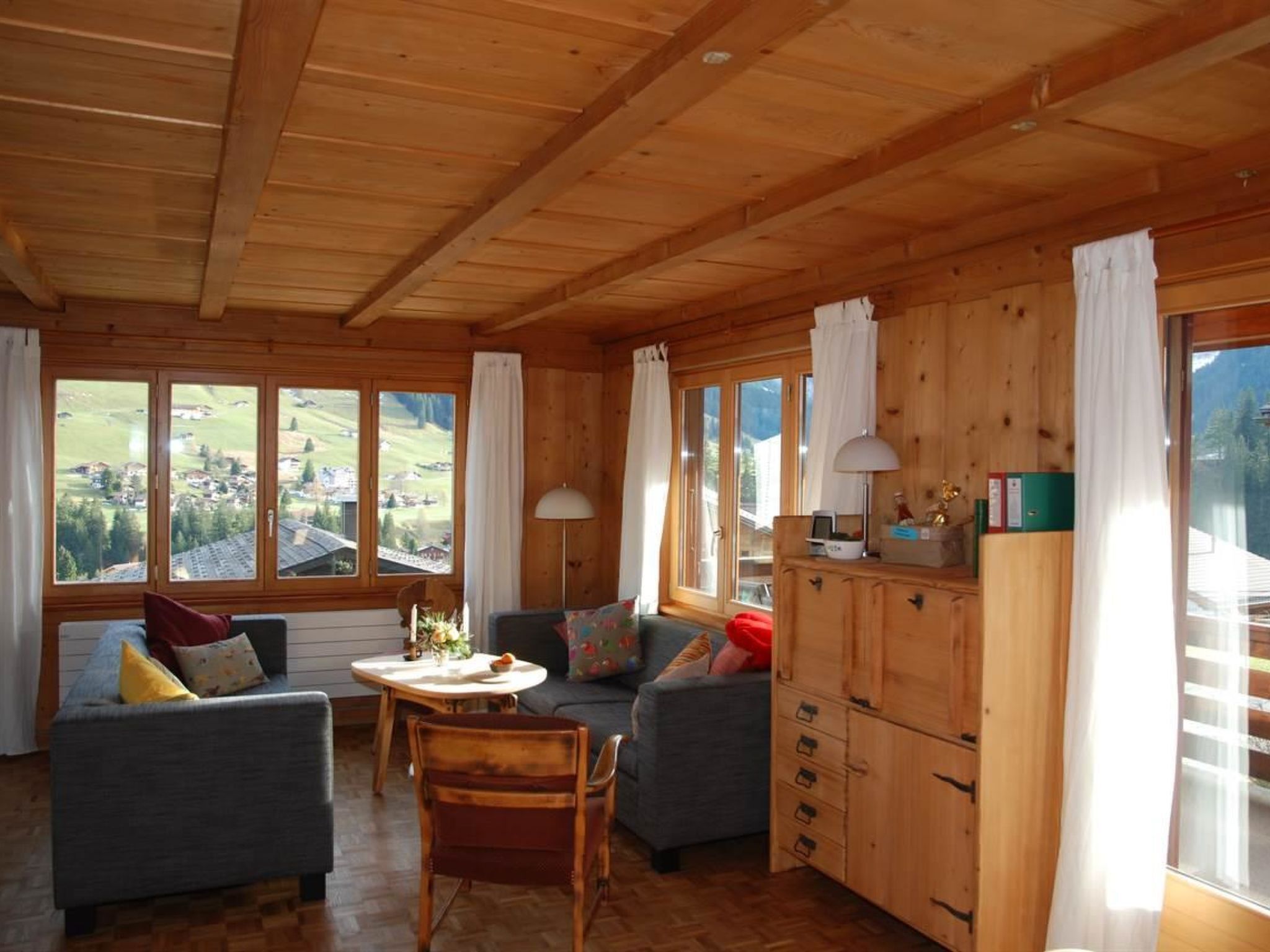 A wooden interior with a dining area, sofas, and a view of the outdoors.