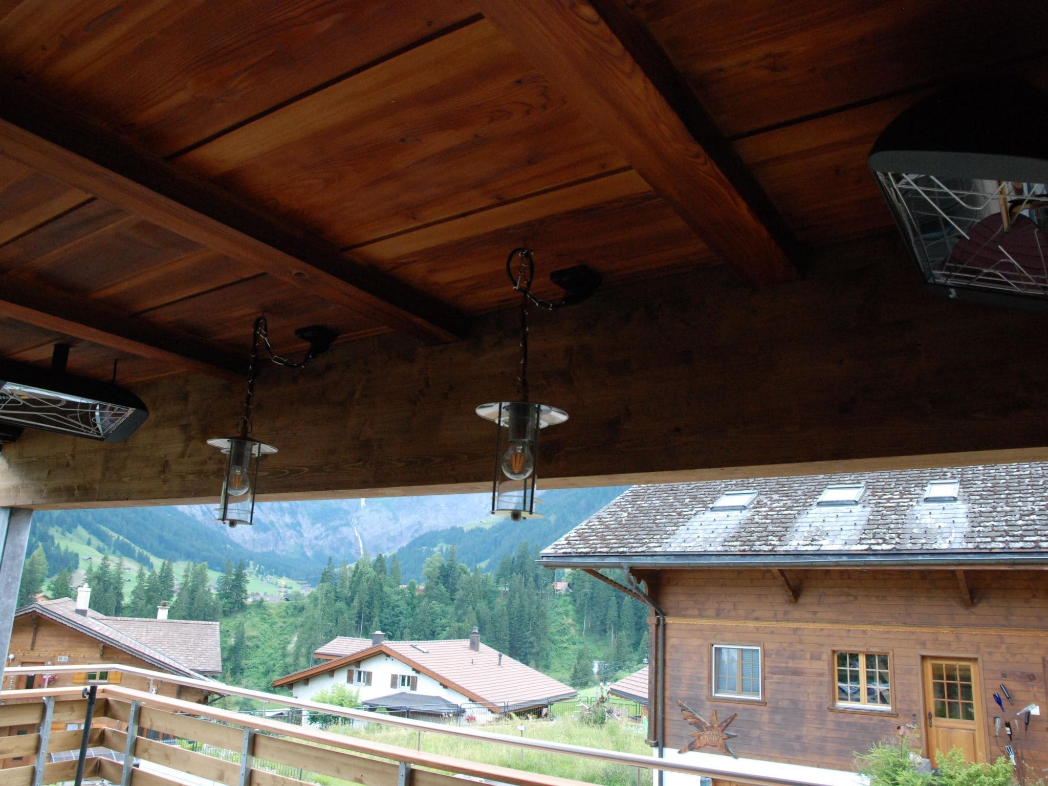 Techo de madera con lámparas colgantes y vistas a un paisaje montañoso.