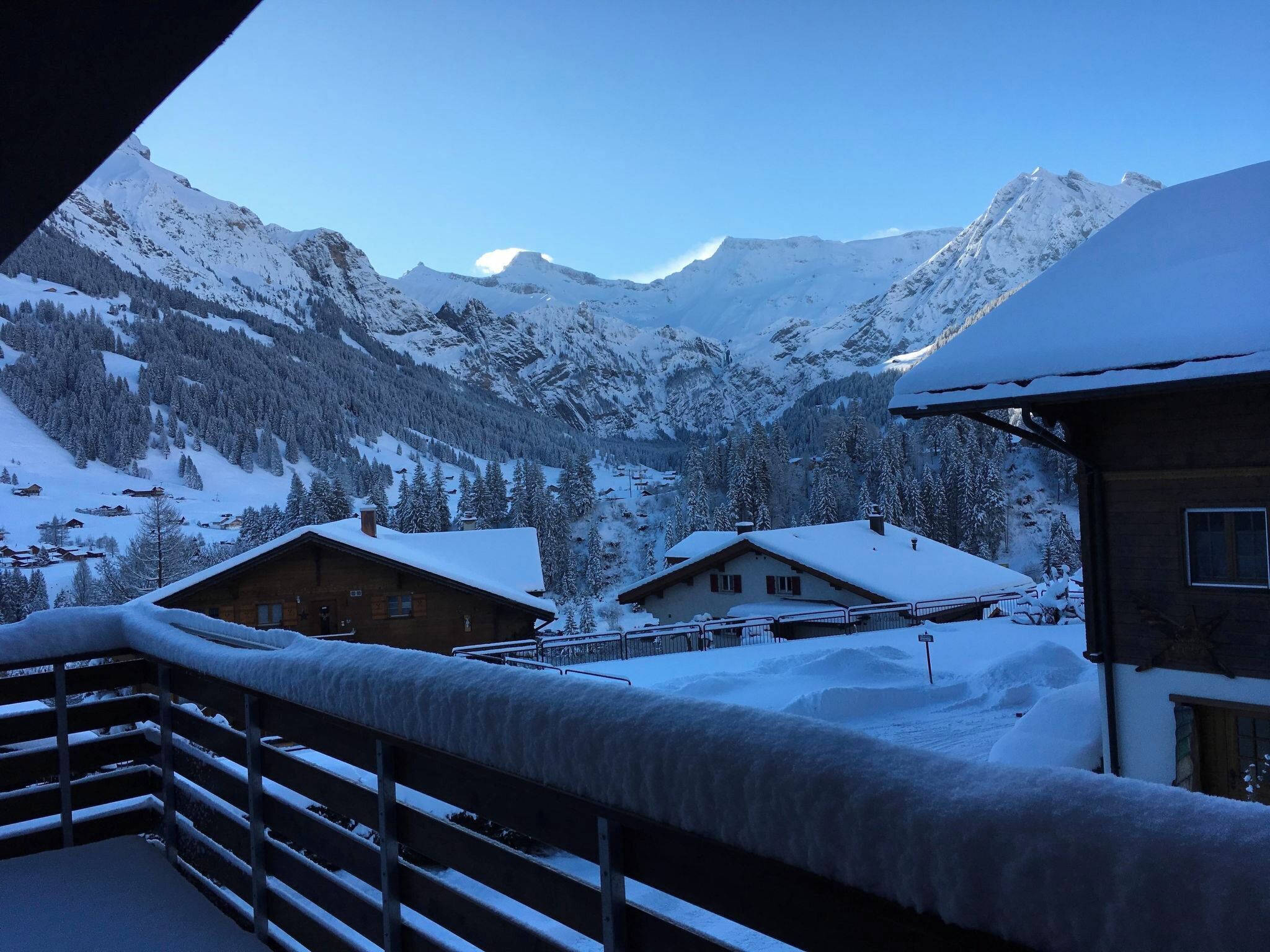 Eine verschneite Berglandschaft mit Holzhütten und einem Balkon aus Holz.