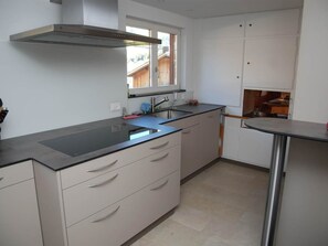 A modern kitchen with a stainless steel range hood, a built-in sink, and light-colored cabinetry. - Hubelhüsi Appartement/Fewo, Dusche oder Bad, WC, 4 oder mehr Schlafräume by Interhome (Adelboden)