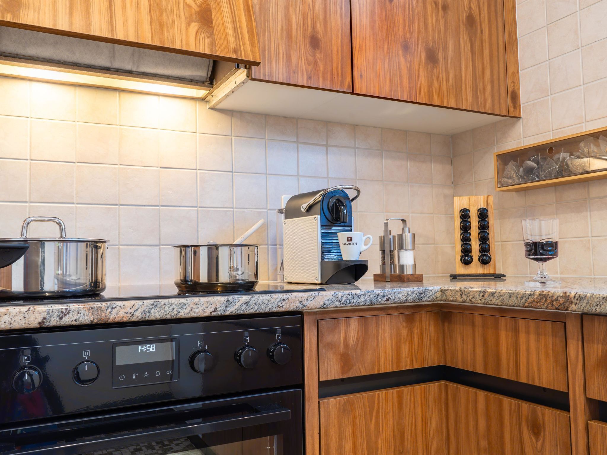 A modern kitchen with wooden cabinets, a stainless steel stove, and a coffee machine.
