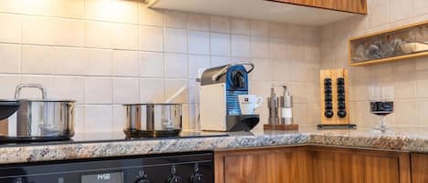 Een moderne keuken met houten kastjes, een roestvrijstalen fornuis en een koffieapparaat.