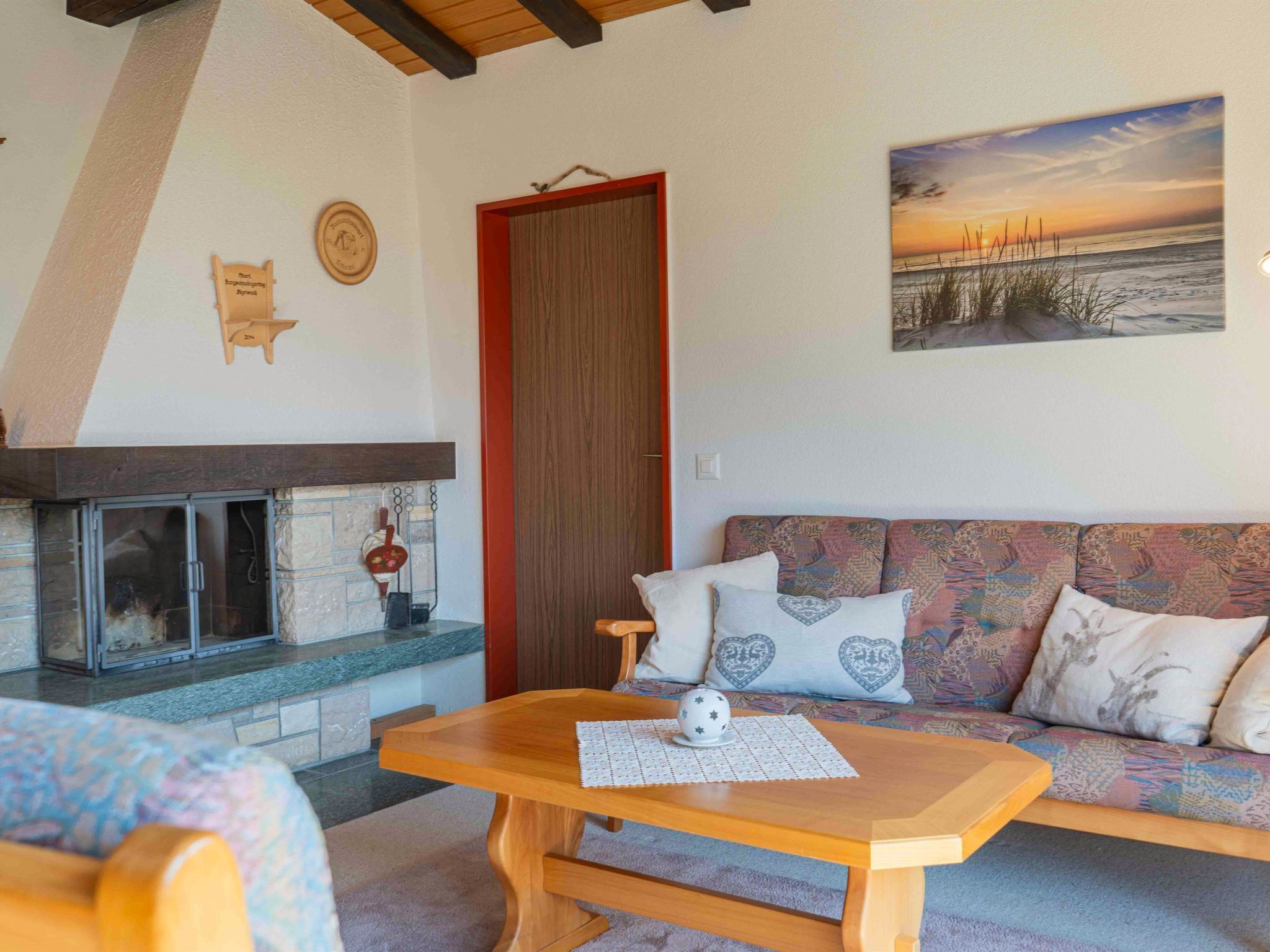A cozy living room with a fireplace, a sofa with patterned cushions, and a table with a decorative object.