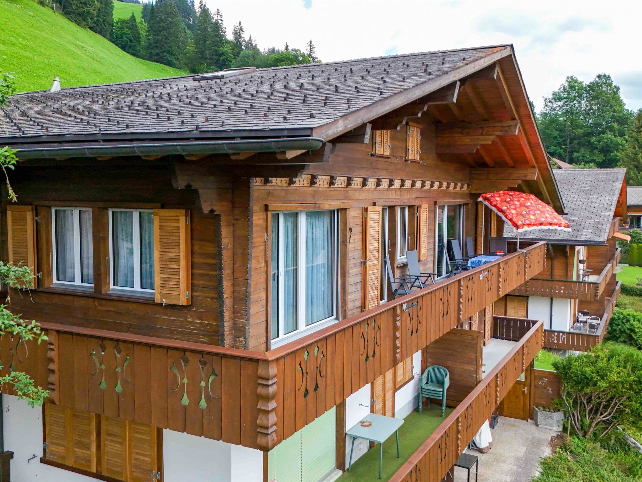 Un chalet en bois à plusieurs étages, doté de balcons, de grandes fenêtres et d’un toit en pente.