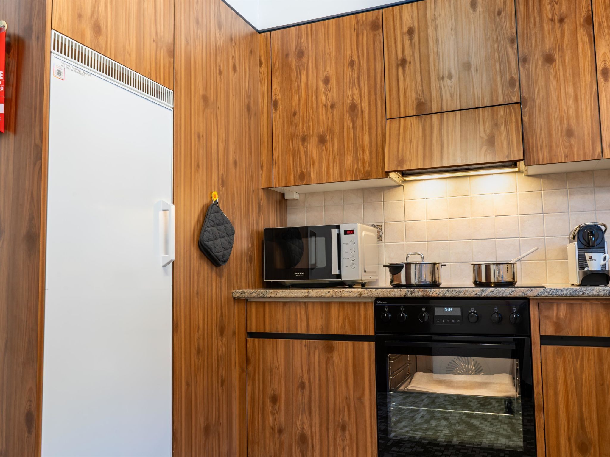 A modern kitchen with wooden cabinets, a white refrigerator, a microwave, a stove, and a dishwasher.
