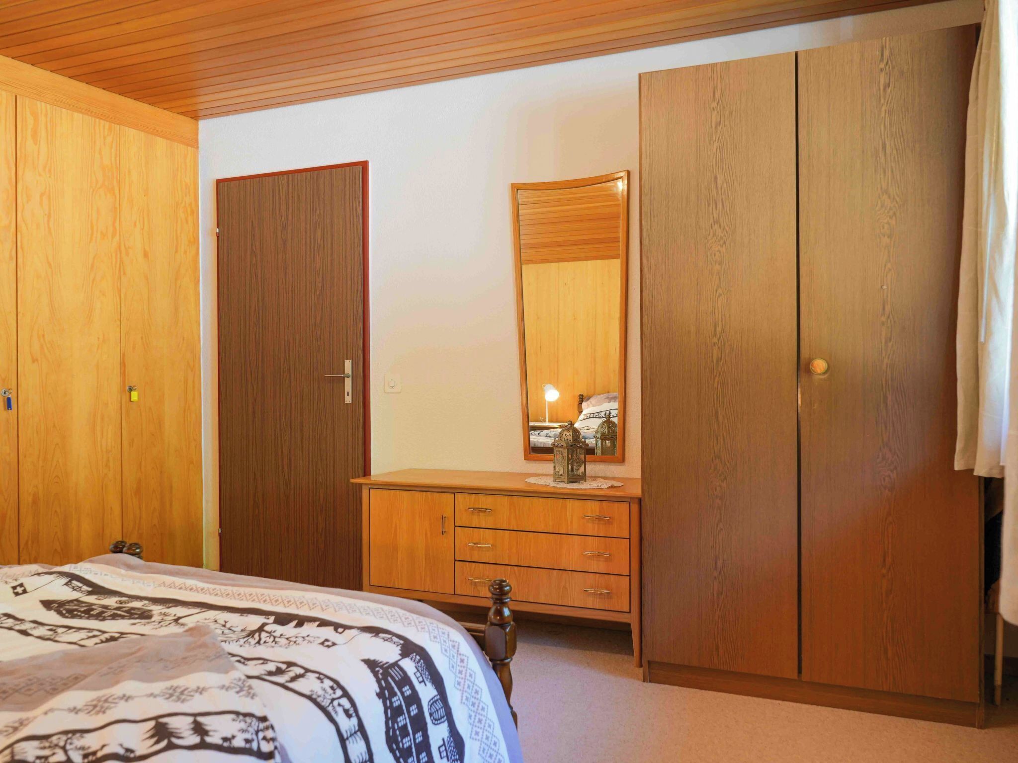A bedroom with a bed, a dresser, a mirror, and two wardrobes.