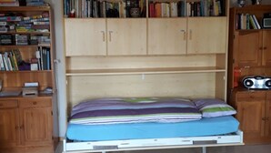 A room with a bed, wooden bookshelves, and a ceiling light fixture. - Adlerhorst Appartement/Fewo, Dusche, WC, 2 Schlafräume 3-Zimmerwohnung by Interhome (Adelboden)