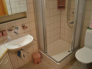 Ein Badezimmer mit Waschbecken, Spiegel und Duschkabine.