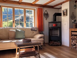 Ein gemütliches Wohnzimmer mit einer Couch, einem Kamin und einem Fenster mit Blick auf Bäume.