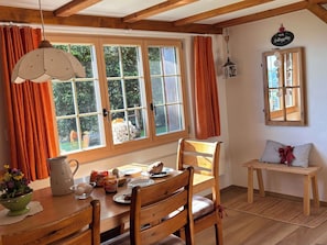 Ein Essbereich mit einem Holztisch, Stühlen und einem Fenster mit Vorhängen.