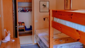 A room with a bunk bed, a desk, a chair, a wardrobe, and a door leading to another room. - Silberdistel  B09 Appartement/Fewo, Bad, WC, 3 Schlafräume 3.5 Zimmerwohnung by Interhome (Adelboden)