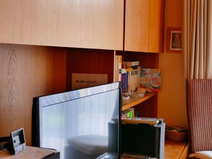 Ein Zimmer mit Schreibtisch, Bücherregal und einem Schild mit der Aufschrift 'WLAN: surfbrett'.