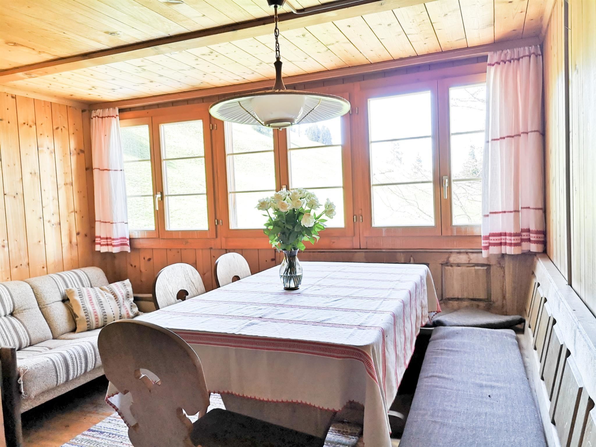 Een houten interieur met een eettafel, bankjes en een bloevas.