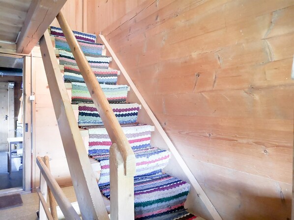 A wooden staircase with colorful, striped carpeting.