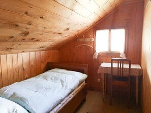 A small, single-bed room with a wooden ceiling and a window.
