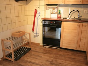 A kitchen with a built-in oven, wooden cabinets, a drying rack, and a hanging towel. - Chalet Bifigen Appartement/Fewo, Dusche, WC 2.5-Zimmerwohnung by Interhome (Kandergrund)