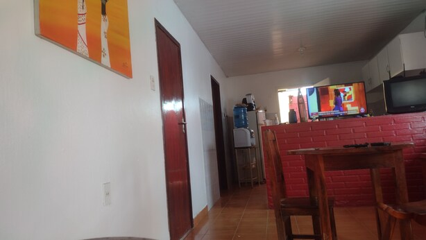 Una sala de estar con una pared de ladrillo rojo, una mesa de comedor de madera y una televisión.