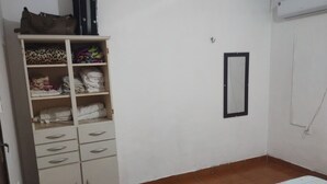 Un dormitorio con armario, cama con colcha estampada y espejo adosado a la pared.