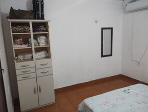 Ein Schlafzimmer mit Kleiderschrank, einem Bett mit floralem Überwurf und einem Wandspiegel.